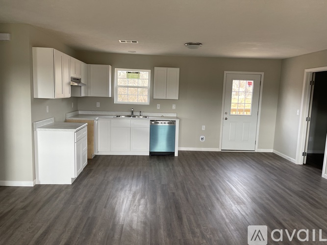 A kitchen with white cabinets and a blue trash can.