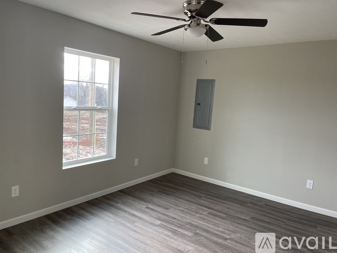 A room with a ceiling fan and a window overlooking a snowy landscape.