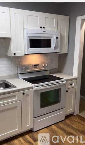 A kitchen with white cabinets and appliances.