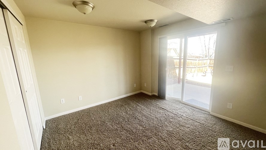 A carpeted room with a sliding glass door leading to a balcony.