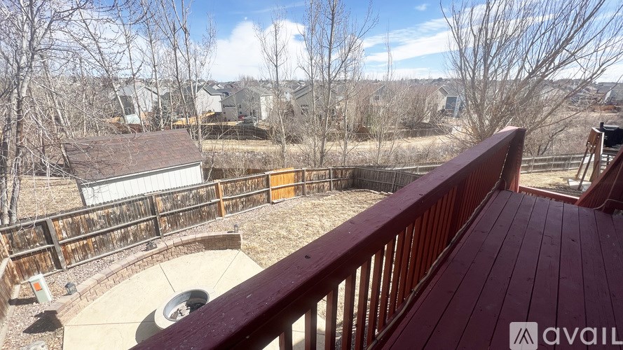 A deck with a railing and a view of a yard and houses.