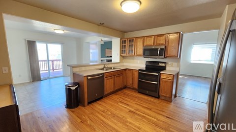 A kitchen with wooden floors and a refrigerator on the right side.