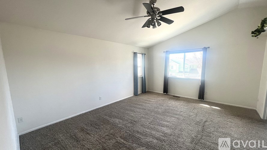 A room with a ceiling fan and carpeted floor.
