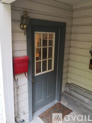 A grey door with a red mailbox on the side of a white house.