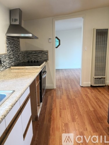 A kitchen with wooden floors and a stone backsplash.