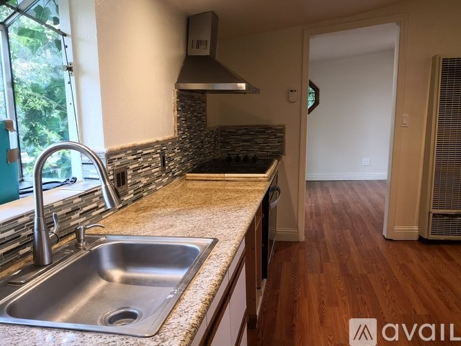 A kitchen with a stone backsplash and a stainless steel sink.