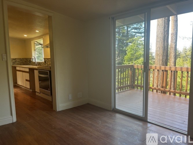 A room with a wooden floor and a glass door leading to a deck.
