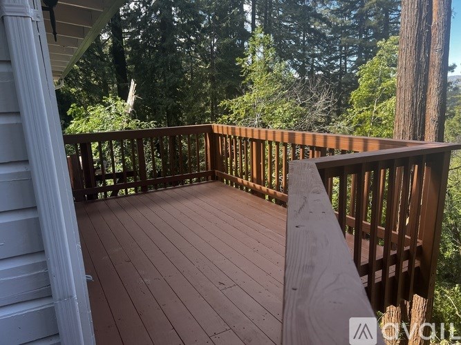 A wooden deck with a railing and trees in the background.
