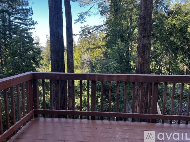 A wooden deck with a railing and trees in the background.