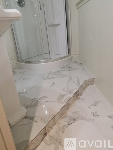 A bathroom with a marble floor and a walk-in shower.