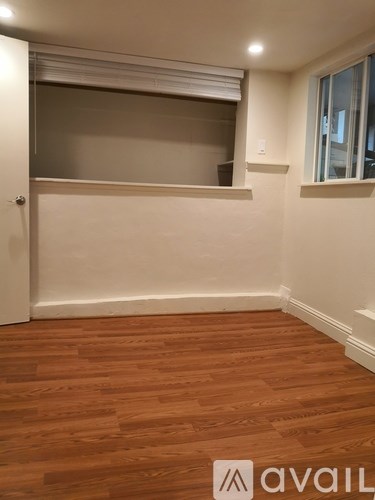 A room with wooden flooring and a window with blinds.