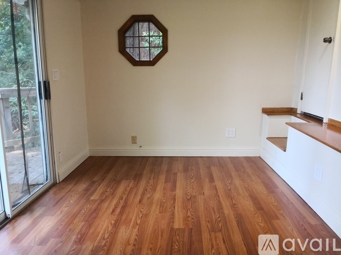 A room with wooden flooring and a hexagonal window.
