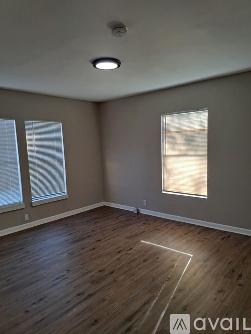 A room with wooden flooring and a window with blinds.