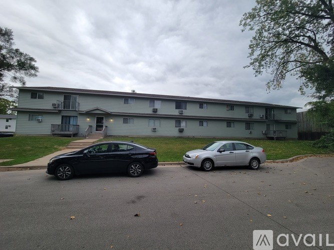 Two cars parked in front of a grey apartment building.