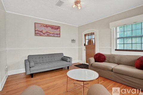 A living room with a grey couch, a white table, and a painting on the wall.