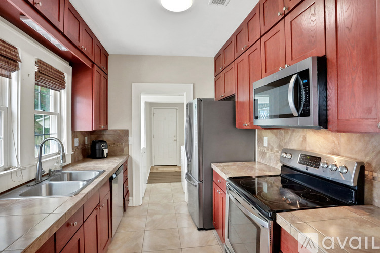A kitchen with red cabinets and a black microwave.