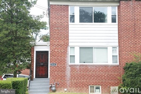 A red brick house with a black door and a window with white blinds.