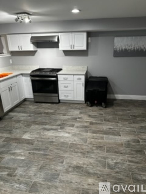 A kitchen with a black stove top oven and a black trash bin.