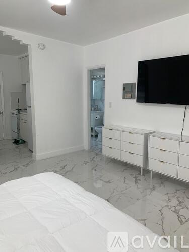 A bedroom with a bed, dresser, and a television.