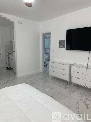 A bedroom with a bed, dresser, and a television.