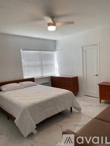 A bedroom with a bed, dresser, and window with blinds.