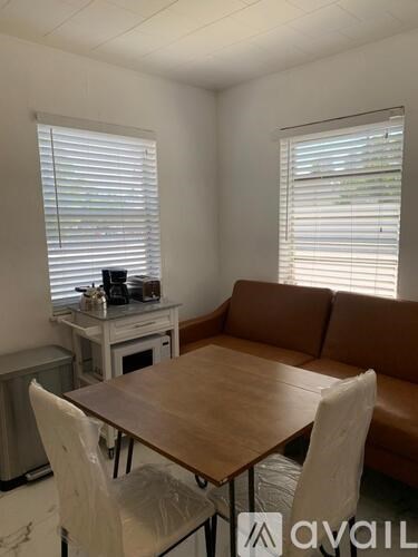 A living room with a brown couch, a wooden table, and a white chair.