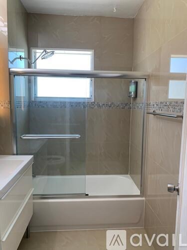 A bathroom with a glass shower door and a white bathtub.