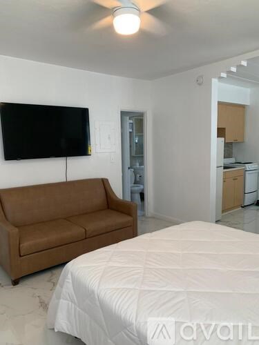 A bedroom with a bed, couch, and television.