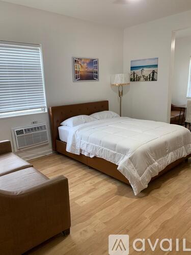 A bedroom with a large bed and a brown chair.