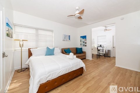 A bedroom with a large bed and a brown chair.