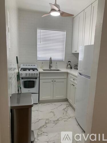 A kitchen with a white stove, sink, and refrigerator.