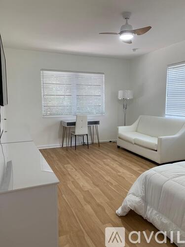 A bedroom with a bed, a couch, a chair, and a ceiling fan.