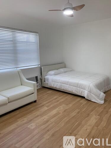 A bedroom with a bed, a chair, and a ceiling fan.