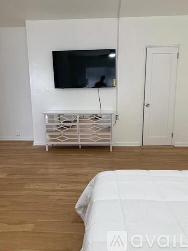 A bedroom with a bed, a television, and a cabinet.