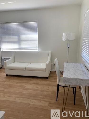 A white couch sits in a room with a marble table and a floor lamp.