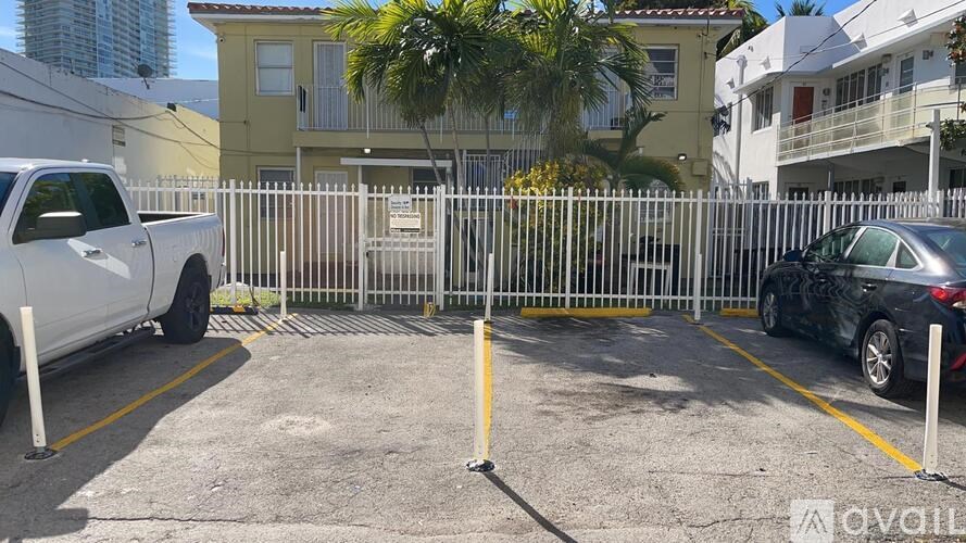 A white truck is parked in a parking lot behind a white fence.