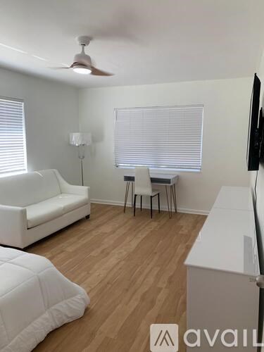 A living room with a white couch, a small table with two chairs, and a television.