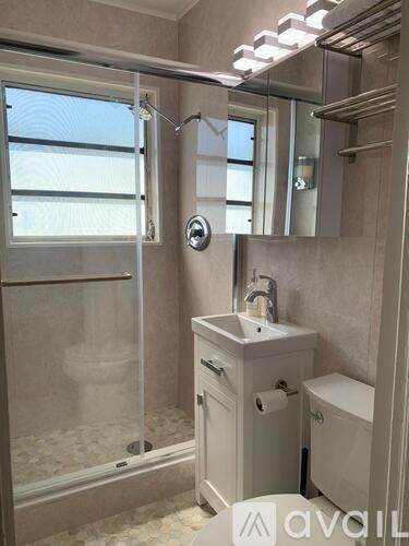 A bathroom with a sink, toilet, and a glass shower door.