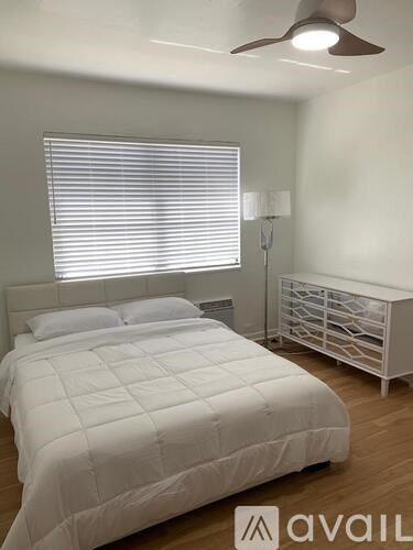 A white bedroom with a large bed and a changing table.