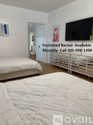 A bedroom with a bed, a TV, and a sign that says "Furnished Rental- Available Monthly- Call 305-998-1398".