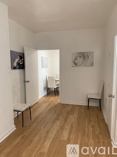 A room with wooden floors and white walls, furnished with a table and chairs.
