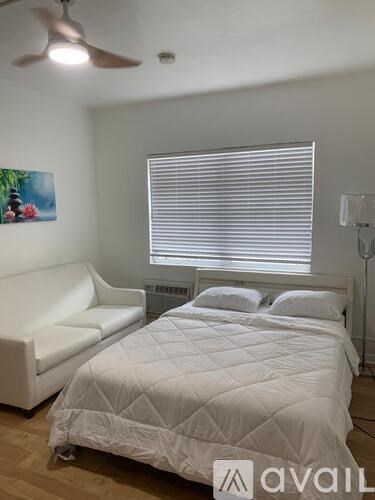 A bedroom with a bed, a couch, and a ceiling fan.