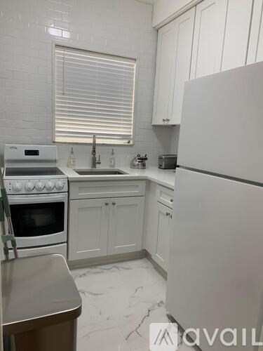 A kitchen with white cabinets and a white fridge.
