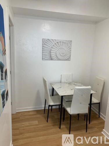 A white dining table with four chairs in a room.
