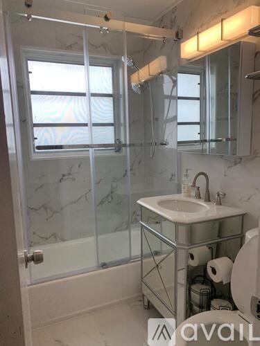 A bathroom with a sink, toilet, and a glass shower stall.