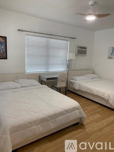 A bedroom with two beds and a ceiling fan.