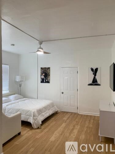 A bedroom with a bed, a ceiling fan, and a white door.