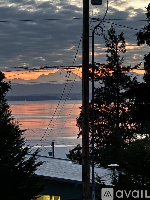 A telephone pole with a sunset view of a lake and mountains in the background.