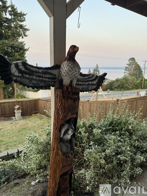 A bird with spread wings is perched on a wooden pole.