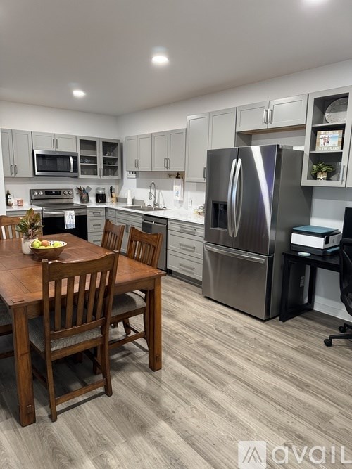 A kitchen with a table and chairs in the foreground and a refrigerator in the background.